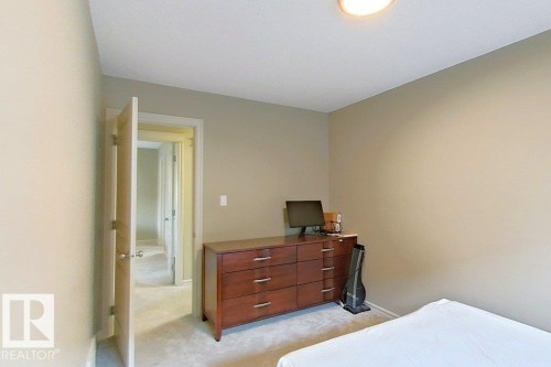 Carpeted room with neutral-toned walls, a flush-mount ceiling light, and a light-colored interior door - 1206 Mckinney Court, Edmonton, AB - Indoor Photo Showing Bedroom