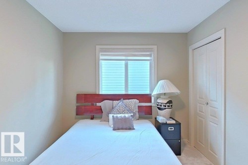 Bedroom featuring neutral wall paint, white trim, a window with blinds, and white bi-fold closet doors - 1206 Mckinney Court, Edmonton, AB - Indoor Photo Showing Bedroom
