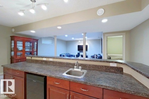 Kitchenette featuring a stainless steel sink, built-in under-counter appliance, and wood-finish cabinetry - 1206 Mckinney Court, Edmonton, AB - Indoor Photo Showing Kitchen