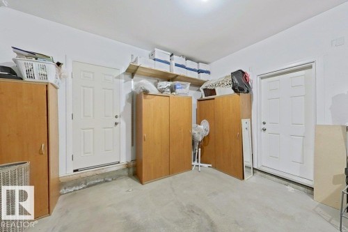 Utility space featuring two white paneled doors, light gray concrete flooring, and an overhead light fixture - 1206 Mckinney Court, Edmonton, AB - Indoor Photo Showing Other Room