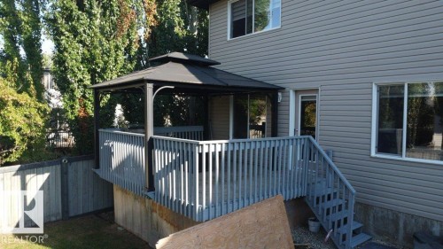 Elevated back deck featuring a black metal gazebo, gray wooden railings, and stairs leading to the lower yard - 1206 Mckinney Court, Edmonton, AB - Outdoor With Exterior