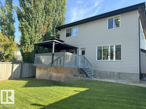 Rear exterior featuring light-toned horizontal siding, a multi-pane picture window, and a ground-level green lawn - 1206 Mckinney Court, Edmonton, AB - Outdoor