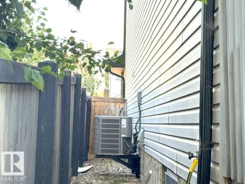 Light-colored horizontal siding facade with a black downspout and an air conditioning unit - 1206 Mckinney Court, Edmonton, AB - Outdoor With Exterior