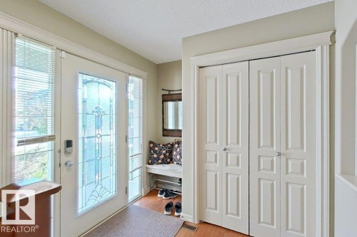 Entryway featuring a decorative glass-paneled door, two side lites with horizontal blinds, and warm wood-finish flooring - 1206 Mckinney Court, Edmonton, AB - Indoor Photo Showing Other Room