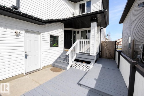 The property features a white exterior with black trim, a gray deck with white railings, and a wooden gate - 3243 26 Street, Edmonton, AB - Outdoor With Exterior