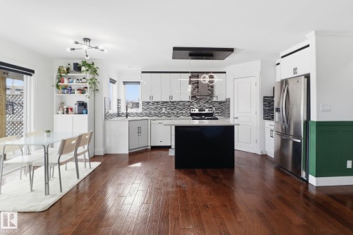 Open-concept living space featuring rich hardwood flooring, a modern kitchen with a central island, and stainless steel appliances - 3243 26 Street, Edmonton, AB - Indoor Photo Showing Kitchen With Upgraded Kitchen