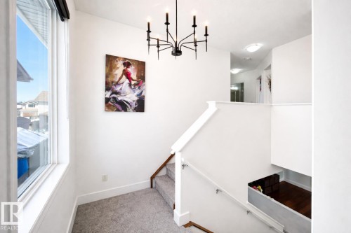 The property features a staircase with carpeted treads and risers, a white railing, and a window providing natural light - 3243 26 Street, Edmonton, AB - Indoor Photo Showing Other Room