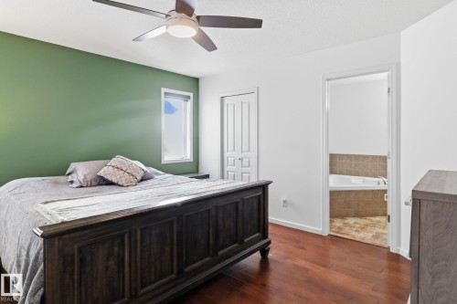 The bedroom features hardwood floors, a ceiling fan with integrated lighting, and a green accent wall - 3243 26 Street, Edmonton, AB - Indoor Photo Showing Bedroom