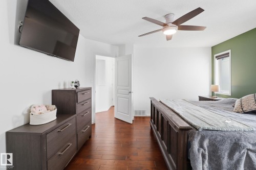 The bedroom features rich hardwood flooring, a ceiling fan with integrated lighting, and a window providing natural light - 3243 26 Street, Edmonton, AB - Indoor Photo Showing Bedroom