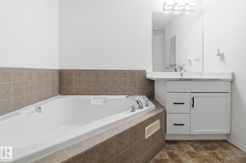Bathroom featuring a built-in bathtub, a vanity with a rectangular sink, and a mirrored medicine cabinet - 3243 26 Street, Edmonton, AB - Indoor Photo Showing Bathroom
