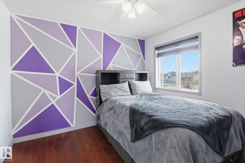 This inviting space features a wall with a geometric design, hardwood floors, and a ceiling fan - 3243 26 Street, Edmonton, AB - Indoor Photo Showing Bedroom