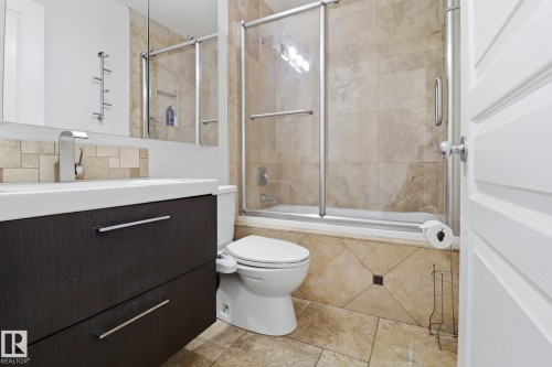 The bathroom features a vanity with a white countertop and a contemporary faucet, a tiled backsplash, and a large mirror - 3243 26 Street, Edmonton, AB - Indoor Photo Showing Bathroom