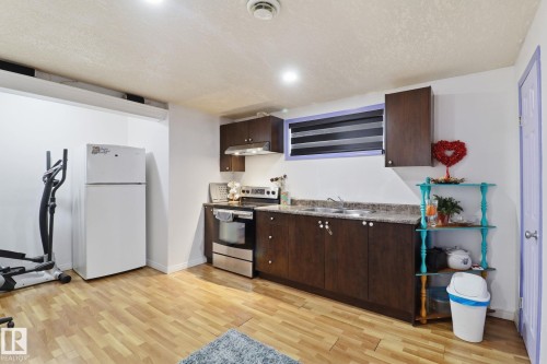 Kitchenette featuring wood-look flooring, dark wood cabinetry, a stainless steel range, and a double basin sink - 3243 26 Street, Edmonton, AB - Indoor Photo Showing Kitchen