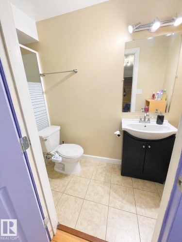 Bathroom featuring tiled flooring, a vanity with a dark cabinet, a mirror with track lighting, and a towel bar - 3243 26 Street, Edmonton, AB - Indoor Photo Showing Bathroom