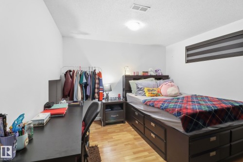 This room features wood flooring, white walls, and a window with horizontal blinds - 3243 26 Street, Edmonton, AB - Indoor Photo Showing Bedroom