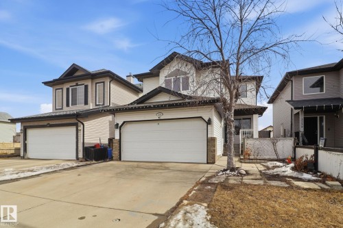 The property features a two-story exterior with light-colored siding, a dark roof, and a prominent front-facing garage - 3243 26 Street, Edmonton, AB - Outdoor With Facade