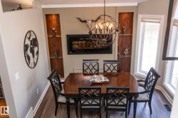Dining area featuring wood-finish flooring, an orb-style chandelier, and a built-in electric fireplace - 