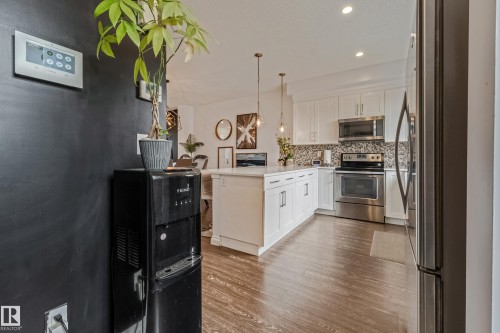 Contemporary kitchen featuring white cabinetry, stainless steel appliances, a center island with pendant lighting, and wood-finish flooring - 8131 Chappelle Way, Edmonton, AB - Indoor Photo Showing Kitchen With Upgraded Kitchen