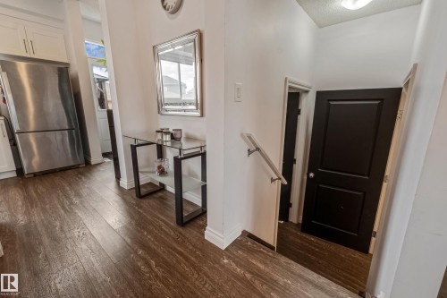 Wood-finish flooring throughout, complemented by a stainless steel refrigerator and white cabinetry - 8131 Chappelle Way, Edmonton, AB - Indoor