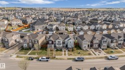 Aerial perspective of a developed residential area featuring multiple single-family homes with diverse architectural styles, asphalt shingle roofs, and paved driveways - 
