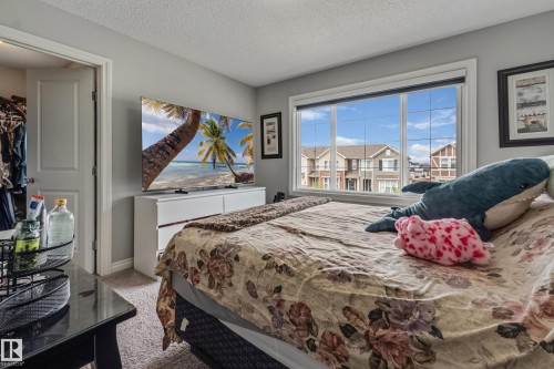 Bedroom featuring neutral gray walls, plush carpet flooring, a large window with white trim, and a white dresser - 8131 Chappelle Way, Edmonton, AB - Indoor Photo Showing Bedroom