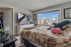 Bedroom featuring neutral gray walls, plush carpet flooring, a large window with white trim, and a white dresser - 