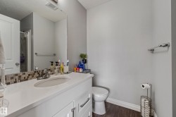 Bathroom featuring a white vanity with an integrated sink, mosaic tile backsplash, and a large mirror - 