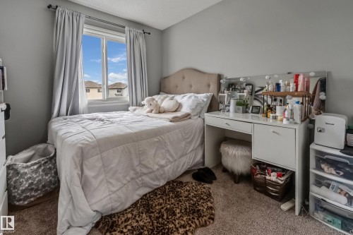 Bedroom featuring a window with natural light, light gray walls, textured carpet flooring, and a built-in vanity with storage - 8131 Chappelle Way, Edmonton, AB - Indoor Photo Showing Bedroom