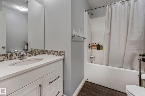 Bathroom featuring a white vanity with an undermount sink, mosaic tile backsplash, and a shower/tub combination with a white surround - 8131 Chappelle Way, Edmonton, AB - Indoor Photo Showing Bathroom