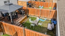 Expansive outdoor deck featuring a dark grey metal gazebo with netting, a built-in wooden planter box, and a privacy fence - 