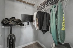 White wire shelving system with integrated hanging rods, grey wall paint, and grey carpet flooring - 