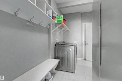 Dedicated laundry area featuring white tile flooring and light gray walls - 