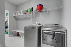 Laundry area featuring light gray walls and white tile flooring - 