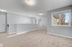 Carpeted upper-level landing featuring a crystal chandelier, recessed lighting, and a large window with roller shades - 