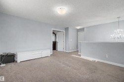 Carpeted room with light gray walls, white trim, and a clear crystal chandelier - 