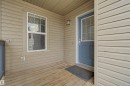 Inviting front porch featuring a wood-finish floor, beige horizontal siding, and a blue entry door with a window lite - 1602 Chapman Way, Edmonton, AB  - Outdoor With Exterior 