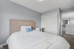 Bedroom featuring light gray wall paint, carpeting, a built-in closet with bi-fold doors, and a built-in desk or vanity area - 