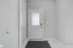Entryway featuring a white door with frosted glass panels, light gray wall paint, white trim, and light-colored tile flooring - 