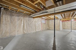 Unfinished basement with concrete flooring, exposed wooden ceiling joists, insulated walls, visible ductwork, and a small window - 