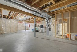 Unfinished basement featuring exposed wood joists, concrete flooring, and visible insulation - 