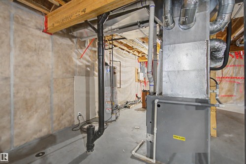 Utility area featuring exposed joists, a water heater, a furnace, and concrete flooring - 1602 Chapman Way, Edmonton, AB - Indoor Photo Showing Basement