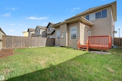 Expansive rear yard featuring a wooden privacy fence, a grass lawn, and a multi-level wooden deck with steps - 