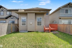 Private fenced backyard featuring a wood deck with railings, natural grass, and a wood privacy fence - 