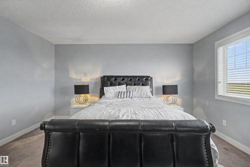 Spacious room featuring light gray walls, white baseboards, a textured ceiling, and a large window with blinds - 1602 Chapman Way, Edmonton, AB - Indoor Photo Showing Bedroom