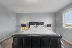 Spacious room featuring light gray walls, white baseboards, a textured ceiling, and a large window with blinds - 