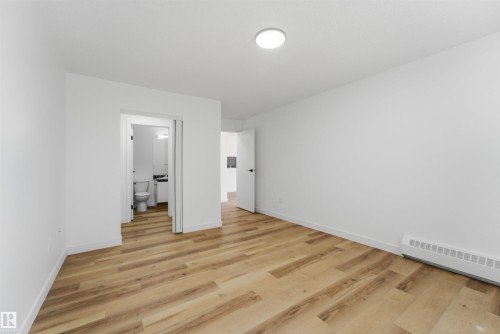 Spacious room featuring light wood-finish flooring, white walls, and a contemporary ceiling light fixture - 302 2508 50 Street Nw, Edmonton, AB - Indoor Photo Showing Other Room
