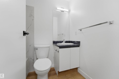 Bathroom featuring a vanity with a dark countertop, an integrated sink, and a wall-mounted mirror - 302 2508 50 Street Nw, Edmonton, AB - Indoor Photo Showing Bathroom