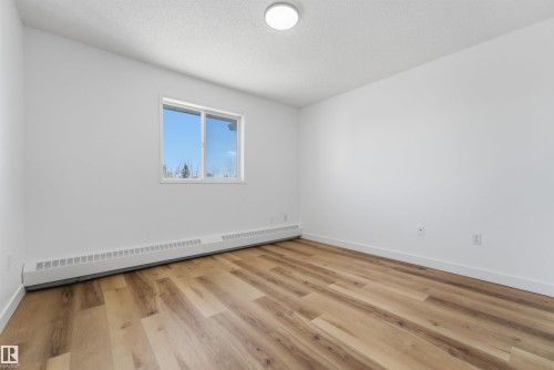 Room featuring wood-finish flooring, white baseboards, and bright white walls - 302 2508 50 Street Nw, Edmonton, AB - Indoor Photo Showing Other Room