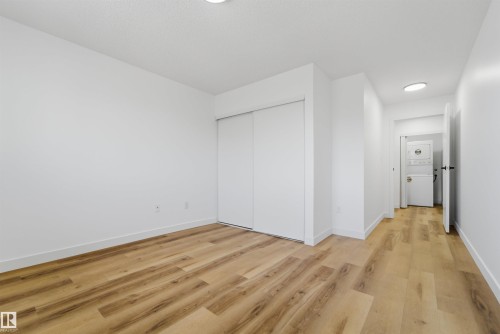 Bright room featuring wood-finish flooring, white walls, and a built-in closet with sliding doors - 302 2508 50 Street Nw, Edmonton, AB - Indoor Photo Showing Other Room