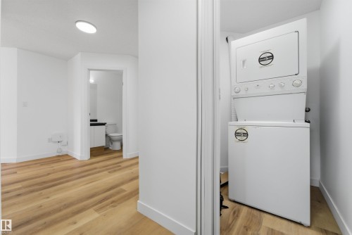 Compact laundry closet featuring a stacked washer and dryer - 302 2508 50 Street Nw, Edmonton, AB - Indoor Photo Showing Laundry Room